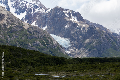 Scenic landscape of a rugged glacier and dark rocky peaks under a cloudy sky in Los Glaciares National Park, Argentina. Concept of harsh cold environment, hiking, adventure and nature