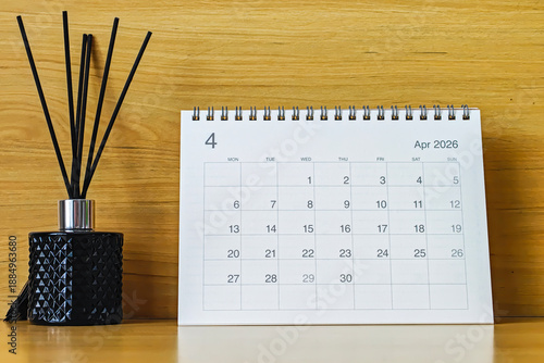 Office desk calendar showing April 2026 with copy space on wooden background, ideal for business planning, scheduling, and time management concepts.