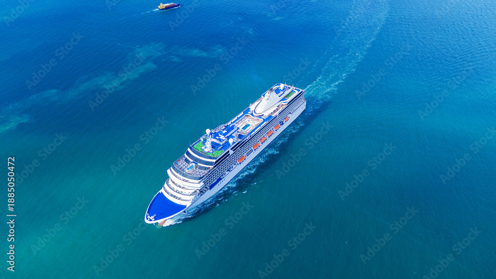 Fototapeta premium a large luxury cruise ship sailing in the deep blue ocean. White passenger vessel featuring swimming pools on the top deck. Summer vacation and international tourism concept.