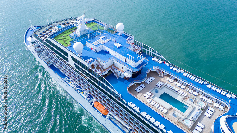 Naklejka premium a luxury cruise ship's open deck featuring a swimming pool, jacuzzis, and rows of sunbeds. Multi-level recreational area with wooden flooring and blue decks over the ocean.