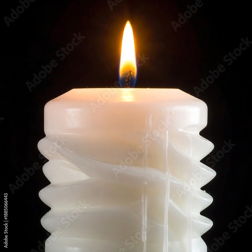 A white candle with a spiral design and a lit flame