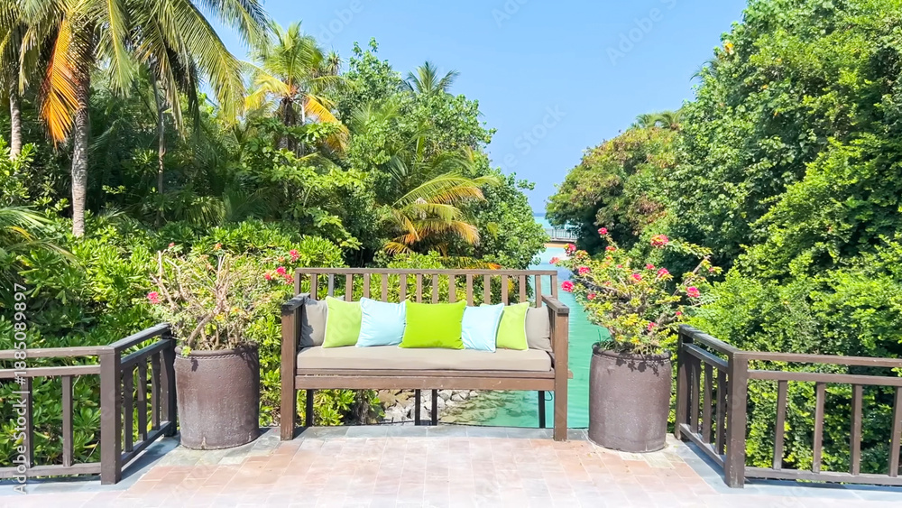 Obraz premium Outdoor wooden bench with colorful pillows overlooking a tropical canal