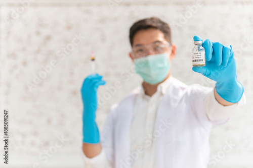 Doctor in white coat holding syringe with vaccine ready for injection and blue protective gloves, holds a syringe ready for an injection
