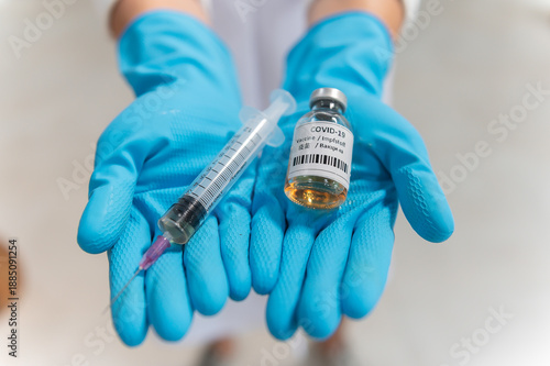 Doctor in white coat holding syringe with vaccine ready for injection and blue protective gloves, holds a syringe ready for an injection