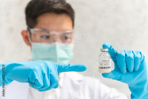 Doctor in white coat holding syringe with vaccine ready for injection and blue protective gloves, holds a syringe ready for an injection