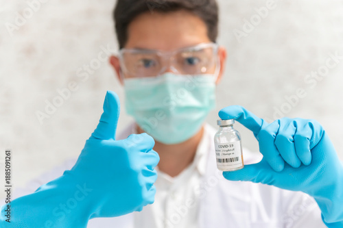 Doctor in white coat holding syringe with vaccine ready for injection and blue protective gloves, holds a syringe ready for an injection