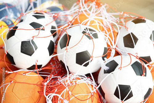 Фотография Group of classic soccer balls and basketballs in red nylon net bags for sports training