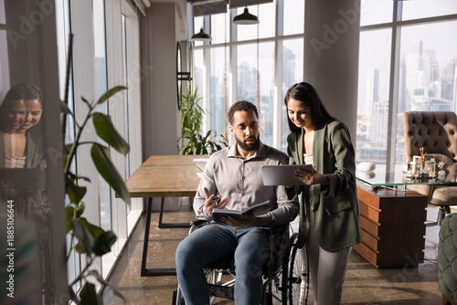 Vászonkép Positive young female manager asking coworker with disability for advice, suppor