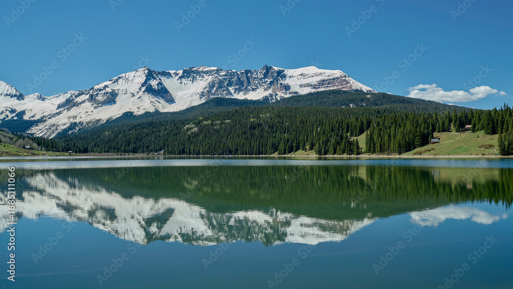 Obraz premium Mountain Lake Reflection with Snow-Capped Peaks and Evergreen Trees