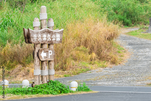 アニメ風の離島の公園入口、手久津久公園の看板と坂道の風景（喜界島・背景素材・コピースペース）