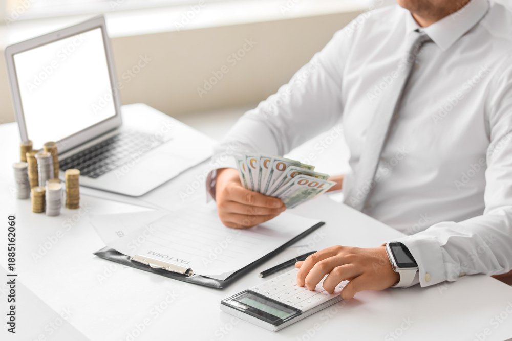 Fototapeta premium Businessman with money using calculator at table in office, closeup. Tax concept