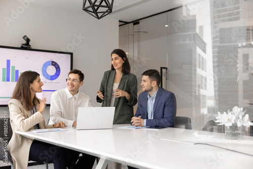 Professional business meeting in modern conference room. Four staff members take part in corporate training or briefing gather together in modern boardroom with laptop, exchanging ideas and solutions