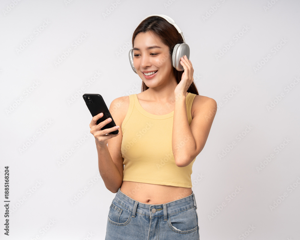 Naklejka premium Beautiful young asian women choose song and play music from smartphone connection with wireless headphone having fun. Teenage girl listen to the music enjoy relaxing on isolated white background.
