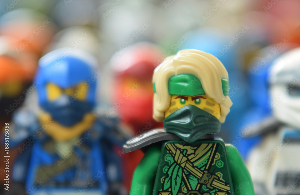 Obraz premium Editorial illustrative image of lego ninjago minifigure of green ninja Lloyd selective focus on blurred background of ninja team.