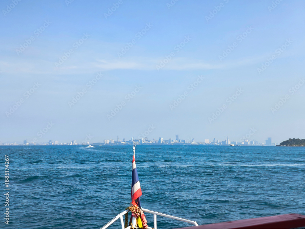 Obraz premium View from the bow of the boat to the sea and the city silhouette in the distance, traveling along the bay on a sunny day.
