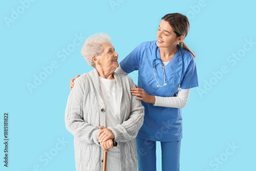 Nurse hugging senior woman with stick on blue background