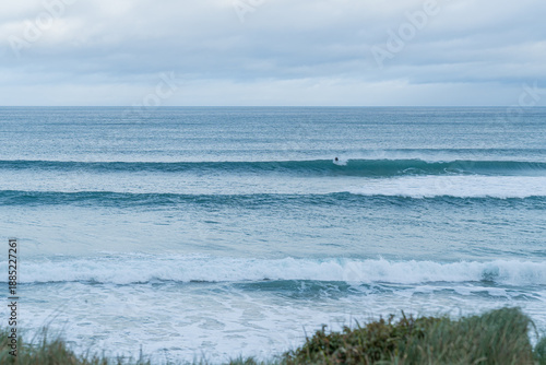 Surfer riding ocean wave with overcast sky
