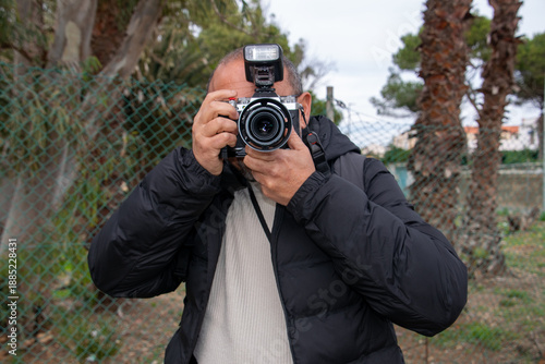 Man with a camera to his face, ready to take a photograph