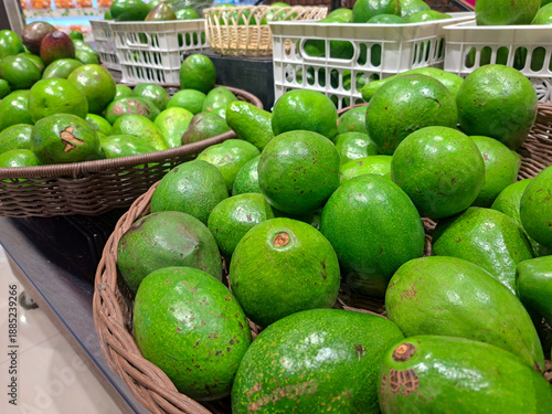 Fresh green avocados displayed in baskets at a market, showing natural texture and ripeness, ideal for concepts of healthy eating, organic produce, grocery shopping, and fresh food.
