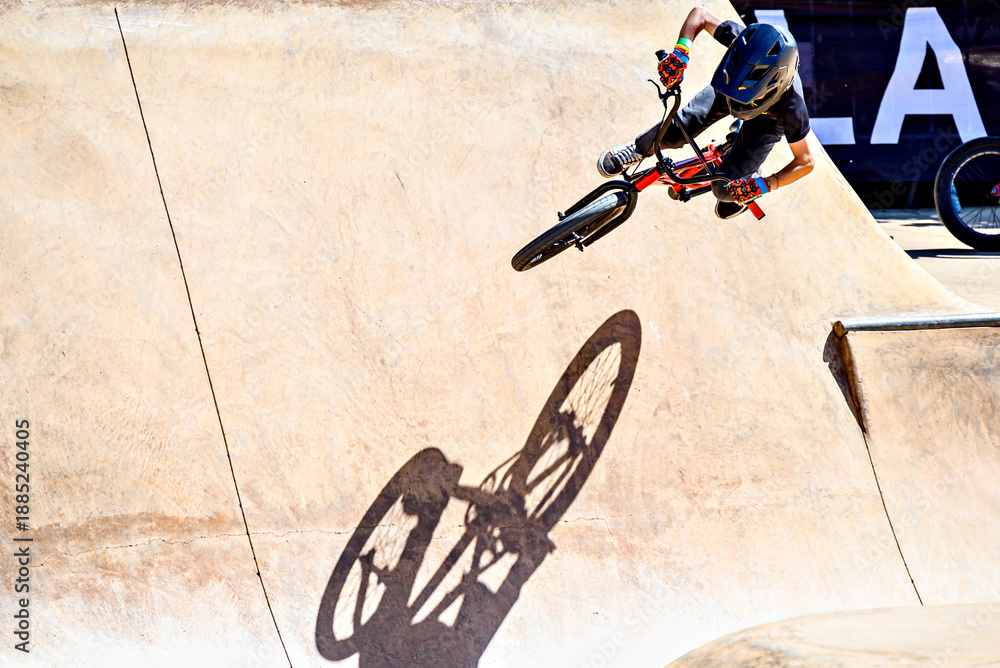 Naklejka premium A young man practicing BMX and performing tricks at the skatepark.