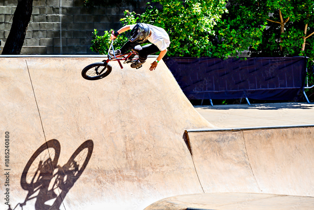 Fototapeta premium A young man practicing BMX and performing tricks at the skatepark.