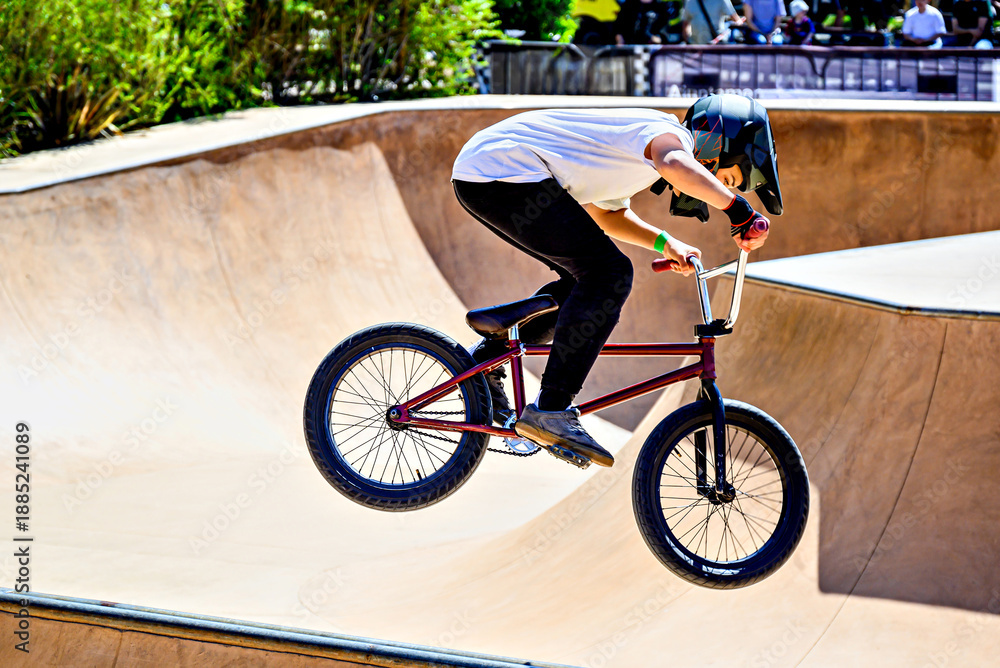 Obraz premium A young man practicing BMX and performing tricks at the skatepark.