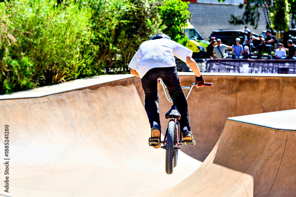 Naklejka premium A young man practicing BMX and performing tricks at the skatepark.