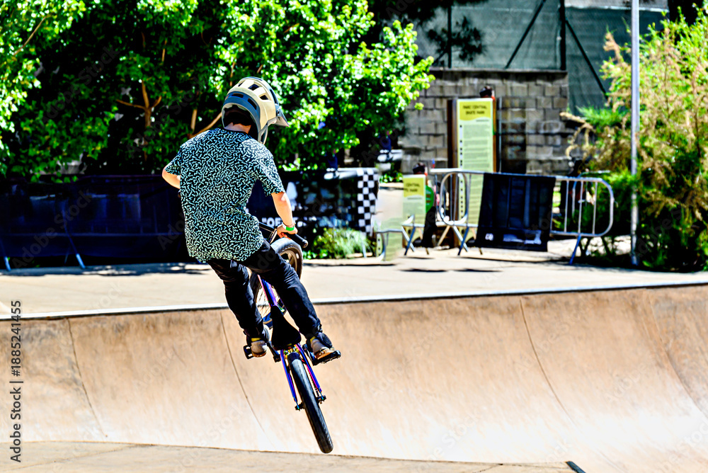 Obraz premium A young man practicing BMX and performing tricks at the skatepark.
