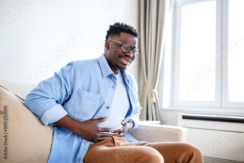 Foto African American Man Suffering from Stomach Ache and Abdominal Pain on Sofa, Bla