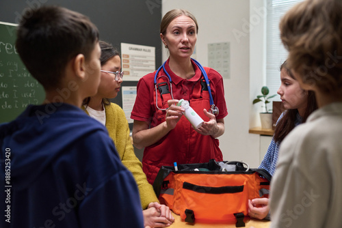 Принти на полотні Caucasian middle aged woman paramedic demonstrating medical equipment to group o