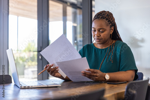 Photography Woman reviewing documents with copper pen beside laptop at office desk, copy spa
