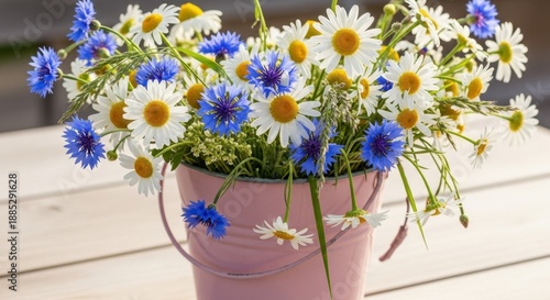 Wallpaper Mural Pink bucket filled with a vibrant bouquet of white daisies and blue cornflowers on a wooden table in natural light Torontodigital.ca