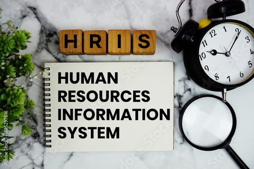 HRIS Human Resource Information System text with alarm clock and magnifying glass on marble background