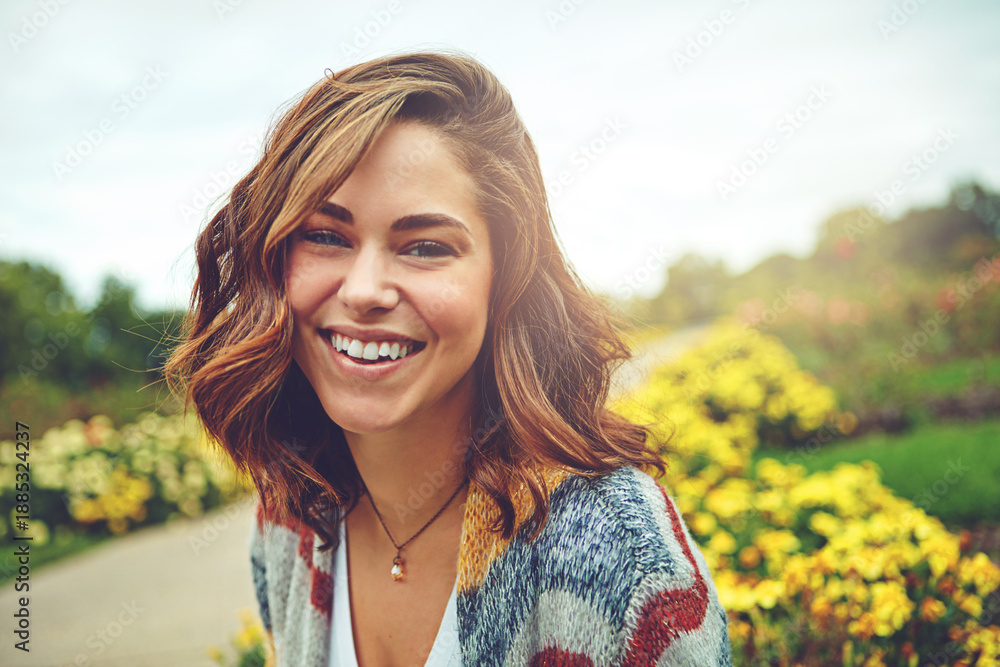 Fototapeta premium Portrait, woman and smile outdoor for travel, spring adventure and holiday trip. Happy, female person and explore nature with floral daisies, sunshine and fresh air on vacation getaway in countryside