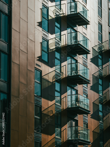 Modern apartment building facade with glass balconies and strong shadows
