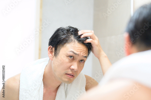 鏡で髪の毛を気にする日本人男性