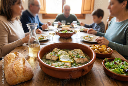 Comida familiar tradicional con merluza en salsa verde servida en cazuela de barro en el centro de una mesa rústica de madera