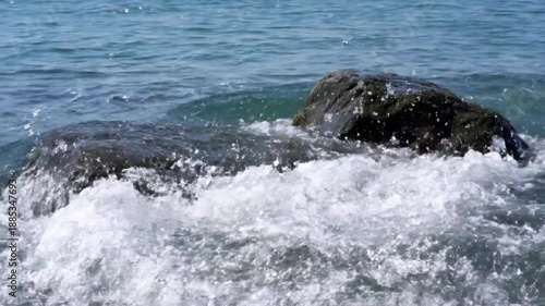 Wallpaper Mural Dark ocean rocks covered in algae stand firm against the clear blue water waves crashing around them Torontodigital.ca