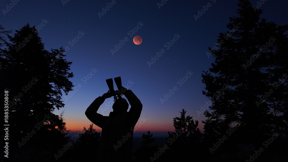 Fototapeta premium Amateur astronomer using binoculars for observing stars, planets, Moon and other celestial objects.