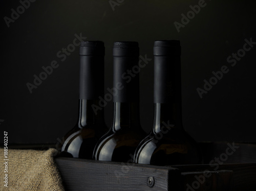 Wine bottles without labels in a wooden box on a dark background