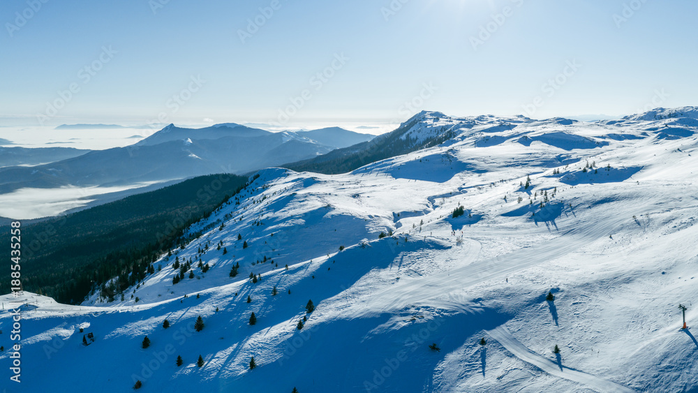 Obraz premium Panoramic alpine mountain view with snowy ridges and distant valleys, captured in winter conditions, representing a well known ski destination and natural landscape