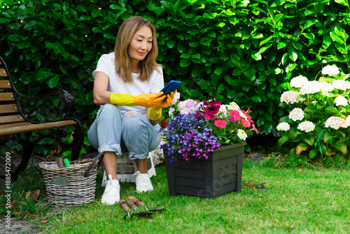 Woman using a phone while gardening in a backyard on a sunny day