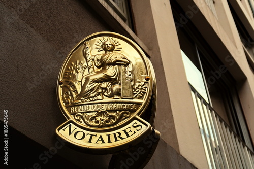 Notaires. Plaque dorée d'office notarial sur façade dans la rue.
