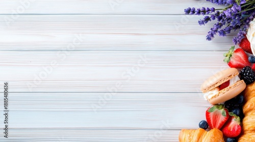 Top-down view of a pale blue wooden surface with a cluster of colorful fruits and macarons in the lower-right