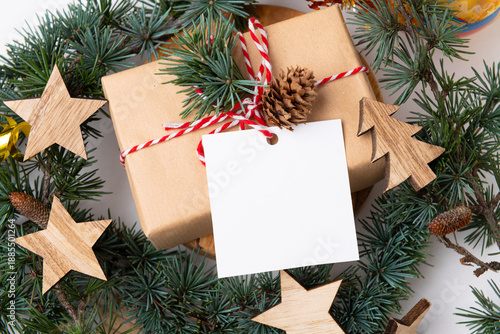 Christmas square paper gift tag mockup on a white background with fir tree branches and decorations top view. Rustic winter composition with blank Gift tag Mockup, close up
