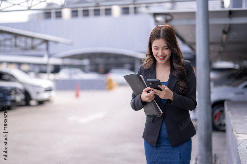 Fototapeta premium Asian businesswoman walking and texting with smartphone smiling