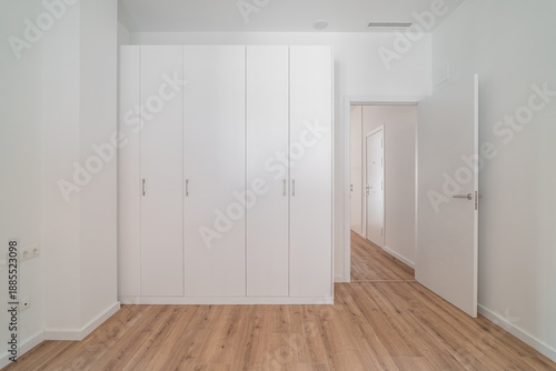 Wallpaper Mural A bright, minimalist interior featuring a white wardrobe and wooden flooring. The walls are plain and the space is uncluttered, emphasizing simplicity and modern design. Torontodigital.ca