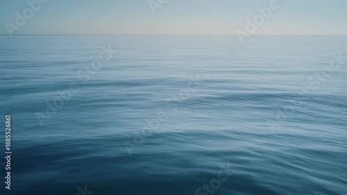 A serene shot showcasing a vast expanse of water under a soft, gradient sky. The water's surface reflects light. Horizontal lines are seen