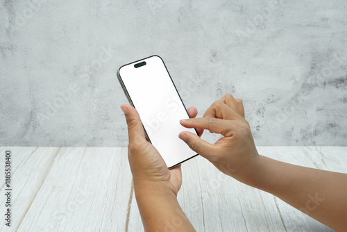 Wallpaper Mural Two hands holding smartphone with blank white screen on bright wooden desk and light wall background. Concept of mobile mockup, app interaction, UI UX presentation, and digital marketing. Torontodigital.ca