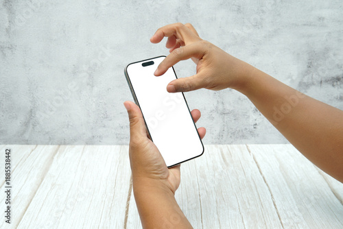 Wallpaper Mural Two hands holding smartphone with blank white screen on bright wooden desk and light wall background. Concept of mobile mockup, app interaction, UI UX presentation, and digital marketing. Torontodigital.ca